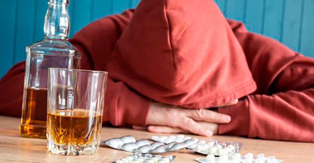 Мужчина спит за столом с таблетками и алкоголем