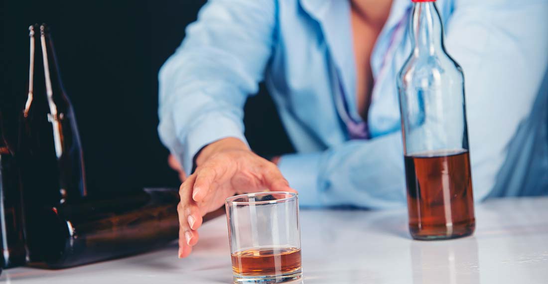 мужчина тянет руку к стакану с алкоголем